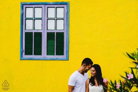Minas Gerais engagement portrait session with yellow painted wall behind the couple.