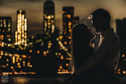 Rim lit silhouette style portrait of a couple with the city skyline in lights