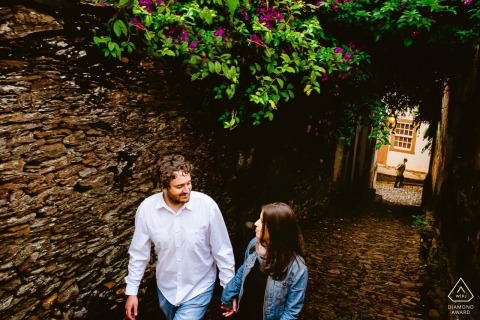 Walking engagement photos of a couple in town with stone walls | Minas Gerais photographer pre-wedding portrait session