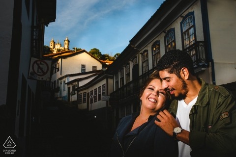 Minas Gerais engagement photos of a couple embracing in the sun with city buildings  | MG, Brazil photographer pre-wedding portrait session