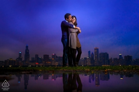 The beautiful, engaged couple cuddled under the sky, in awe of the blue and purple tones at dusk, with the city skyline at their feet, and love wrapped all around them The Chicago, IL couple cuddled under the sky of blue and purple tones