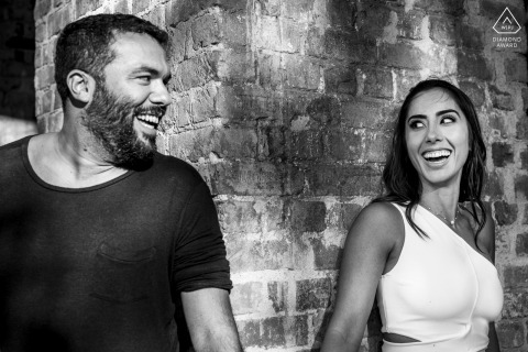 Rio de Janeiro, Brasil engaged couple hold hands and peek around the corner of a brick building at each other