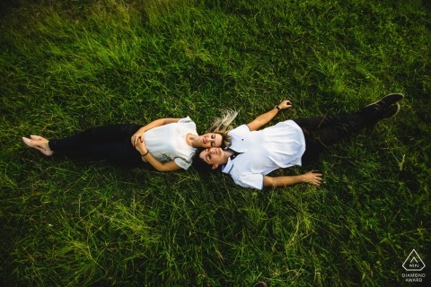 A couple lays head to head together on the grass in Ouro Preto during their engagement photoshoot by a Minas Gerais, Brazil photographer.