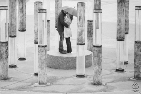 A couple kisses under an umbrella surrounded by water fountains in Tacoma, Washington A couple kisses under an umbrella surrounded by water fountains in Tacoma, Washington