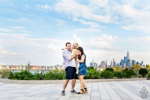 Standard poodle jumps up into arms of couple at Steven's Institute of Technology during their Hoboken NJ engagement photo session 