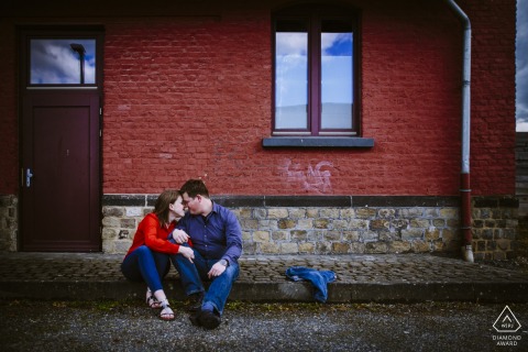 Engagement Photography with a red brick wall Aachen, Germany Engagement Photography - Image contains: red, brick, sitting, couple, cobblestone