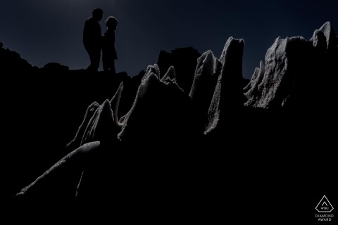 Silhouette eines Paares in der Atacama-Wüste, eingerahmt von einer Eisscholle, während einer Verlobungsfotosession.