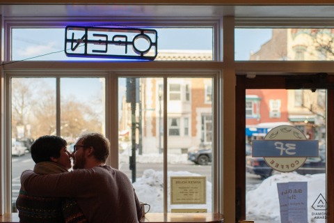 A couple snuggles by the window of a cafe in Albany, NY