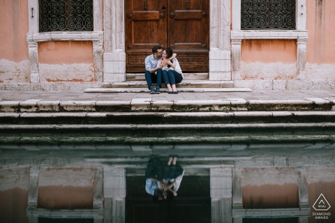 Venecia (Italia) Sesión de compromiso con una pareja sentada en los escalones con su reflejo en el agua