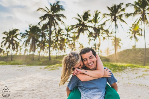 Maceió, Brazil couple e-session at the beach with a piggy back laughing hug on the sand