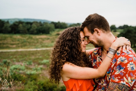 On location Heath, West Sussex couple engagement portrait shoot in red shirts near an open field in the country 