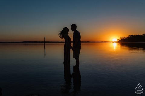 Photo de fiançailles pittoresque de Fartura au coucher du soleil avec des silhouettes marchant sur l'eau