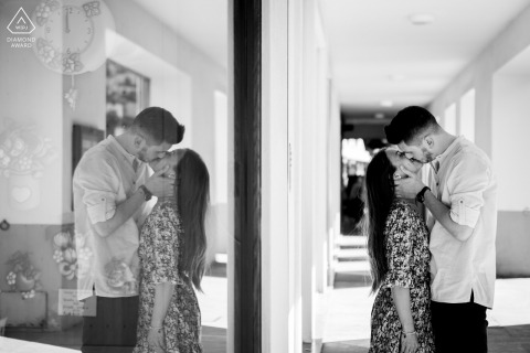 Lovere post proposal portrait session with a Brescia engagement photographer of a Lake Iseo couple taking A walk at the Lake Side with BW glass reflections and a kiss