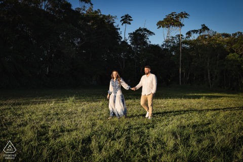 A Save the Date in Petropolis. Rio de Janeiro portrait in Brazil of a couple walking hand in hand in an open field under a low sun 