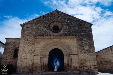 A Baeza modern couple poses for an announcement portrait in the arch of a stone building for their Jaen engagement