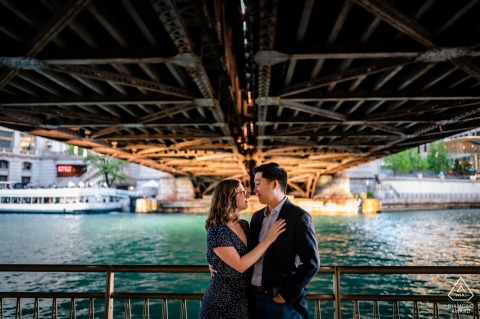 Chicago Riverwalk engagement announcement photo idea showing a couple standing under a bridge during sunset 