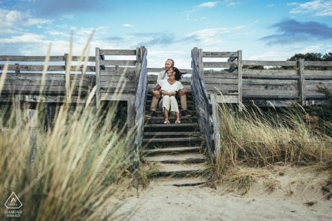 Le Touquet Paris Plage destination engagement shoot for a French Couple hugging on the boardwalk stairs by the sand