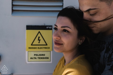 Retrato de noivado de estilo de vida não tradicional no deserto do Atacama de um casal sul-americano posando ao lado de uma caixa de painel elétrico