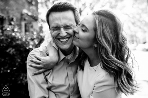 The woman joyfully kisses his cheek as he grins, captured in a black and white image taken in Georgetown, Washington DC