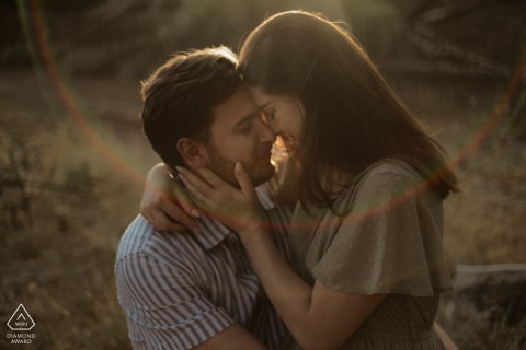 A loving couple poses together in a beautiful location called Le Porge, capturing an intimate and tender moment illuminated by warm tones and a subtle lens flare