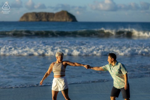 A couple joyfully embraces each other while playing on the picturesque beach during their engagement session in Manuel Antonio, Costa Rica