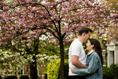 Couple enjoying a joyful moment under a cherry blossom tree, surrounded by historical buildings on Holywell Hill in St Albans