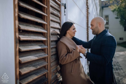 In the picturesque Gödöllői kastély, a couple in love share an intimate portrait session, leaning against a charming wall in the quiet building nooks, captured by an experienced wedding photographer