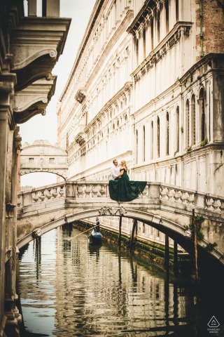 Romantisches Paar, aufgenommen in einem Verlobungsporträt auf der Brücke der Sehenswürdigkeiten über dem Wasser in Venedig von einem talentierten und künstlerischen IT-Hochzeitsfotografen.