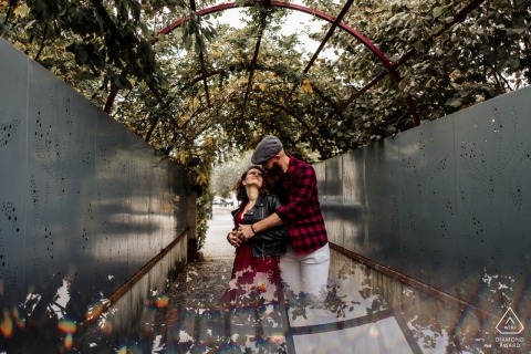 Engaged couple lovingly embraces in a nature setting, surrounded by the picturesque trellis arches of Dreux, Eure-et-Loir garden, captured beautifully by a top Dreux wedding photographer.