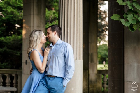 In the enchanting gardens of Harkness Park, this engagement portrait by a CT wedding photographer features a couple leaning against a column, immersed in the timeless beauty of their surroundings in Waterford, CT
