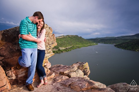 A pre-wedding engagement portrait captures a couple's joyful embrace with shared laughter high above Horsetooth Reservoir in Fort Collins, Colorado.