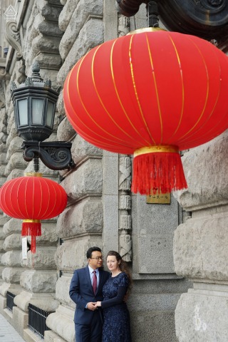 A fine art couple portrait by a Shanghai wedding photographer on the Bund in China, standing and holding hands under the red lantern during Chinese Spring Festival.