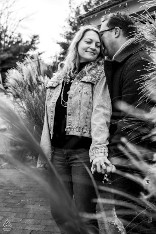 The photograph showcases a vintage monochromatic portrait session of a newly engaged couple at The Inn at Sugar Hill, captured from a distance behind foliage.