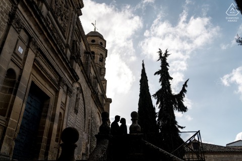 In Baeza, Jaén, Spain, a photo was taken before the wedding, showing a couple standing close together, with the sun setting and old buildings in the background.