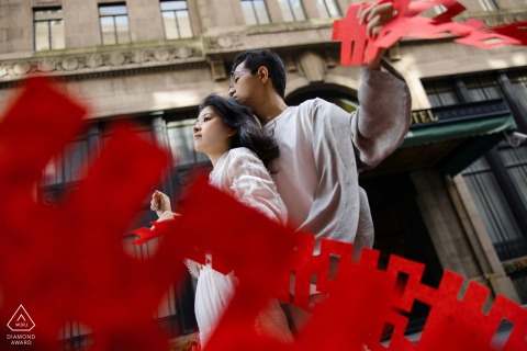 At The Bund in Shanghai, China, long strips of the Chinese characters, symbolizing happiness, adorn the scene. These decorations create a multilayered picture, reflecting the joy and cultural significance of engagements and weddings.