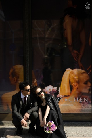 At The Bund in Shanghai, China, a simple window display featuring a stylish couple in sunglasses transforms in to a captivating scene, blending fashion and elegance against the iconic city backdrop.
