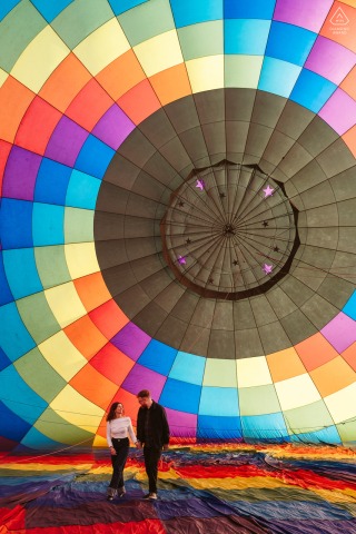 This beaming couple poses for their pre-wedding portraits in a vibrant hot air balloon at Fair Winds Balloon Flights in Lafayette, CO.