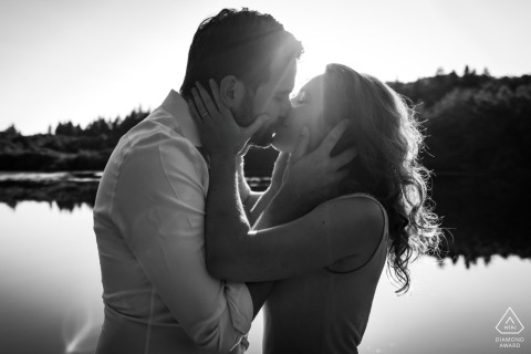 A passionate kiss at the water in Autun, captured in a backlit black-and-white shot, emphasizing the couple's love.