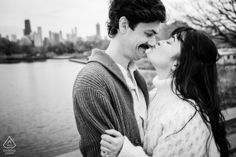 In Chicago's Lincoln Park, a bride-to-be playfully kisses her groom on the nose. The scene exudes warmth and joy, framed by the park's lush greenery and serene atmosphere.