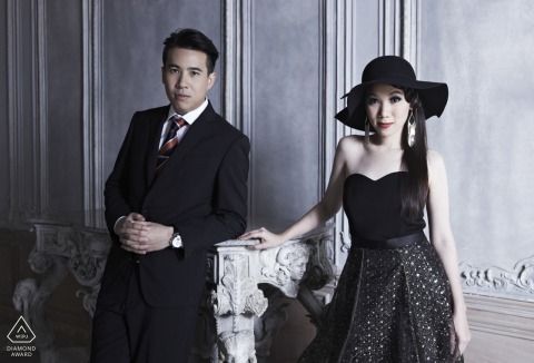 In Bangkok, Thailand, a couple exudes elegance in formal clothing, both looking directly at the camera. This sophisticated portrait is expertly captured by a skilled WPJA photographer.