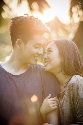 Sunlit Embrace in Bangkok: A Warm and Inviting Portrait of Love and Happiness In Bangkok, Thailand, a couple stands embracing and smiling, warmly backlit by the sun. This inviting portrait is beautifully captured by a talented WPJA photographer.