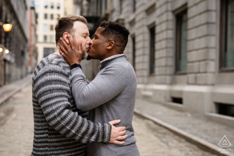 In Old Montreal, an engaged couple shares a kiss on a charming cobblestone street, expertly captured by a skilled WPJA photographer.