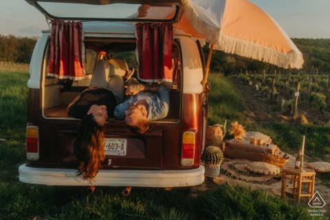 A couple lies comfortably inside a retro van in Bannay, smiling and relaxed, capturing the intimacy of their engagement.