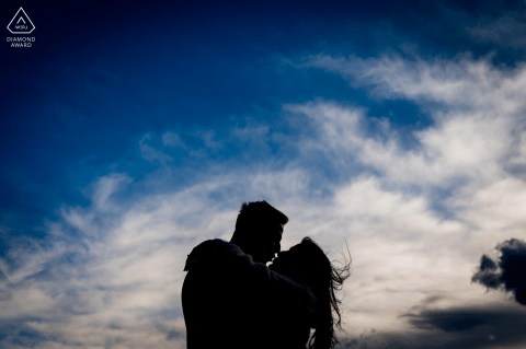 In Charly, France, a minimalist portrait features a couple kissing with their silhouetted forms set against a dramatic sky, artfully captured by a skilled WPJA photographer.