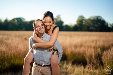 Playful Love at Washington Crossing Park: Groom Carries Bride Through Lush Fields Surrounded by Nature’s Beauty The groom playfully carries his bride on his back through lush fields at Washington Crossing Park, surrounded by nature's beauty.