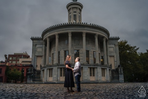 The couple lovingly gaze into each other's eyes, enveloped in warmth, outside the elegant Merchant Exchange Building.