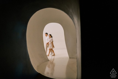 The couple strolls through egg-shaped doors at Bangkok's MOCA Museum, surrounded by modern architectural design.