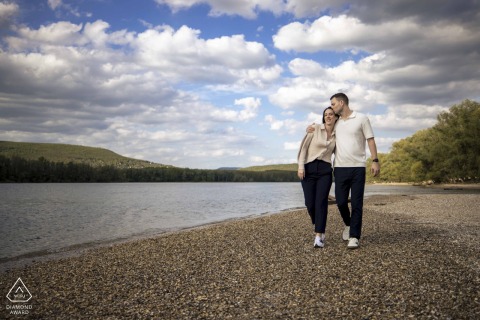 A couple walks hand-in-hand at sunrise beside a peaceful lakeside in Szigetcsúcs.