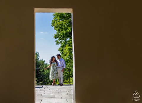 A couple stands outside in Hampstead Heath, London, perfectly framed by a doorway, creating an intimate engagement portrait.