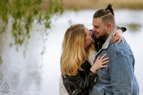 Intimate Lakeside Portrait In Jarry Park: Couple Surrounded By Serene Natural Beauty In Montreal Engagement Session A couple poses for an intimate portrait by the water in Jarry Park, Montreal, surrounded by serene natural beauty.